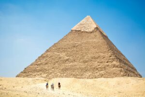 People Riding A Camel Near Pyramid Under Blue Sky